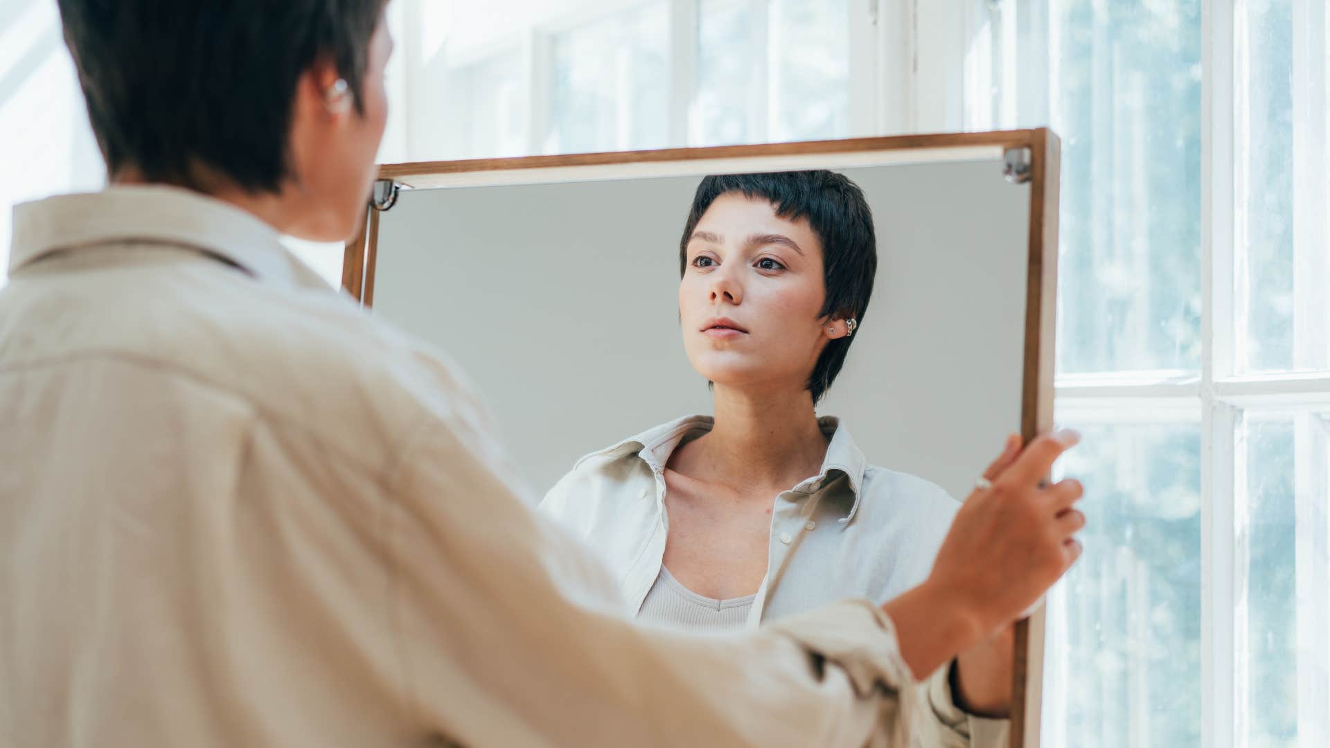 self-conscious woman looking in mirror refusing imperfection
