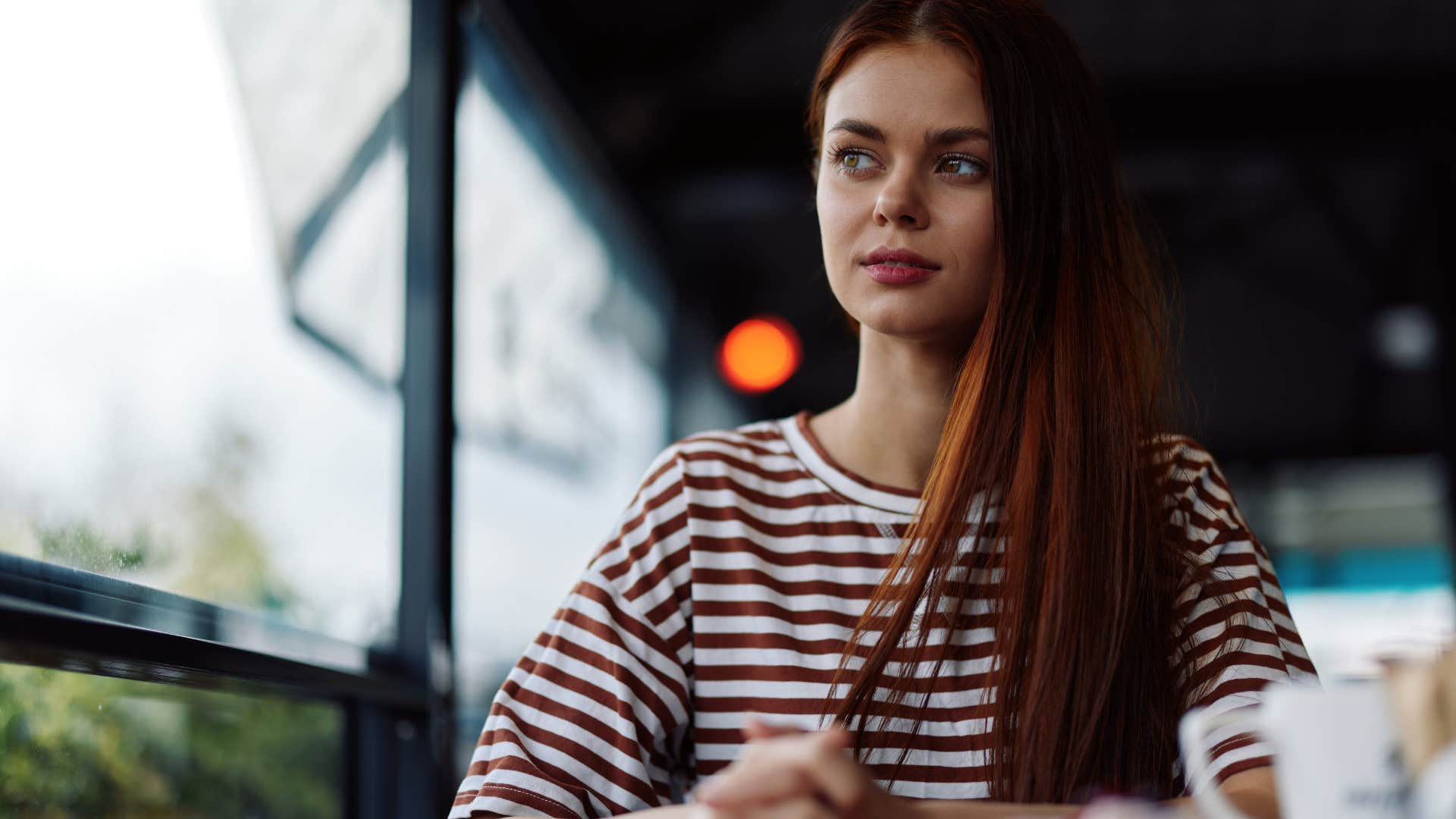 Woman whose hard times are coming to an end sitting oudoors clamly in a cafe