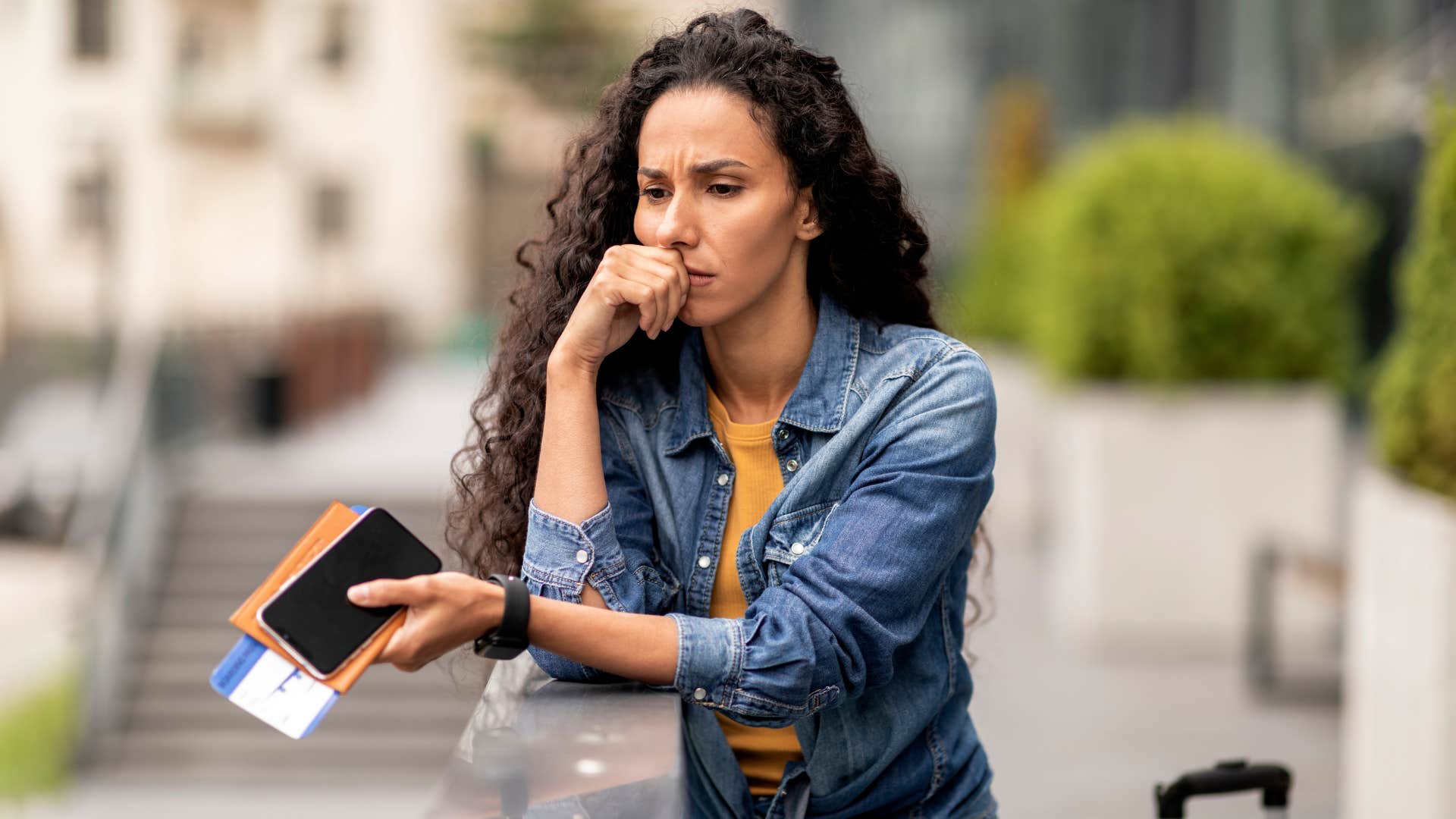 woman avoids checking her bank statements as she thinks deeply while outside