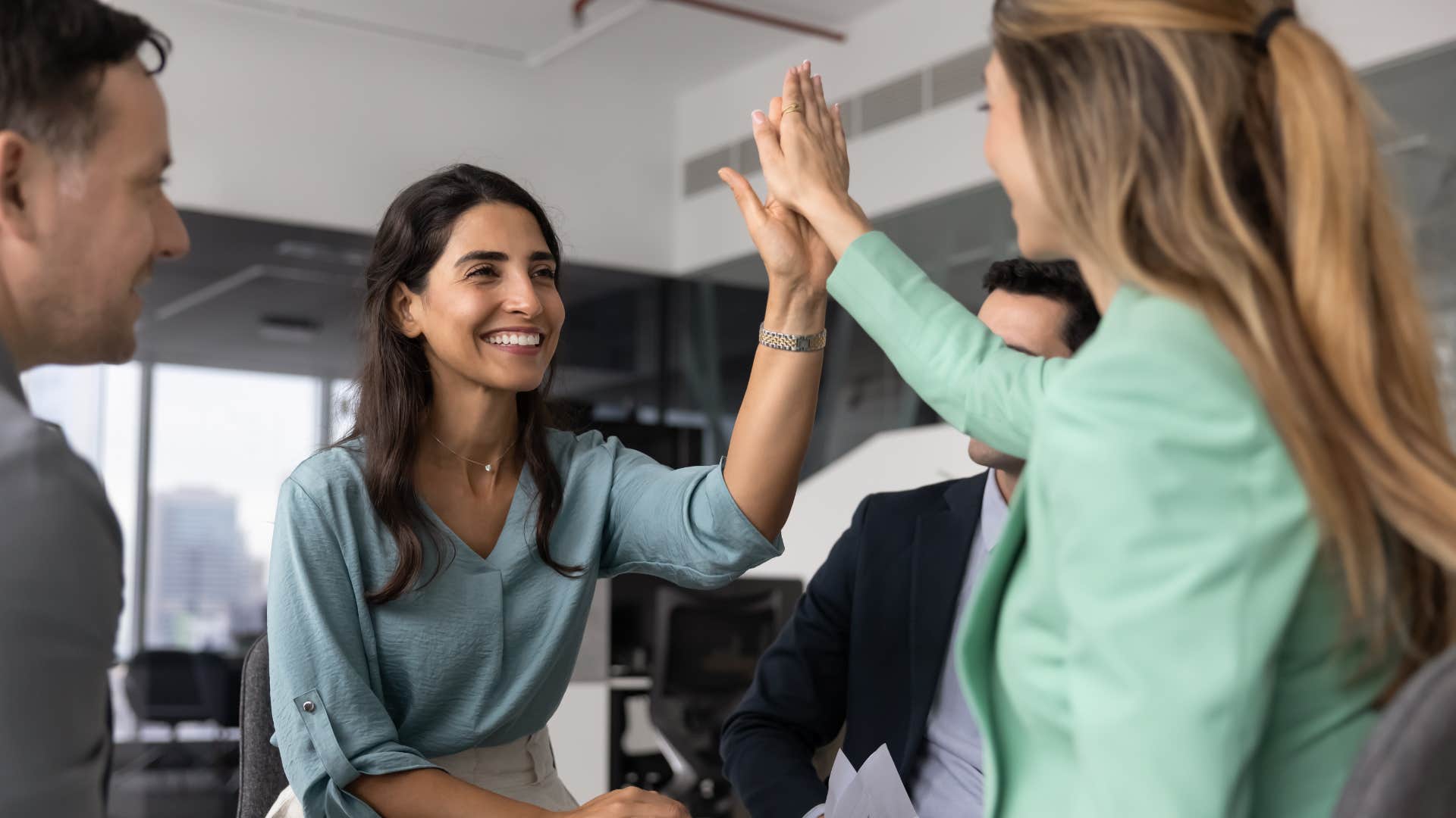 female coworkers high fiving one another as woman smiling says i'm fine constantly