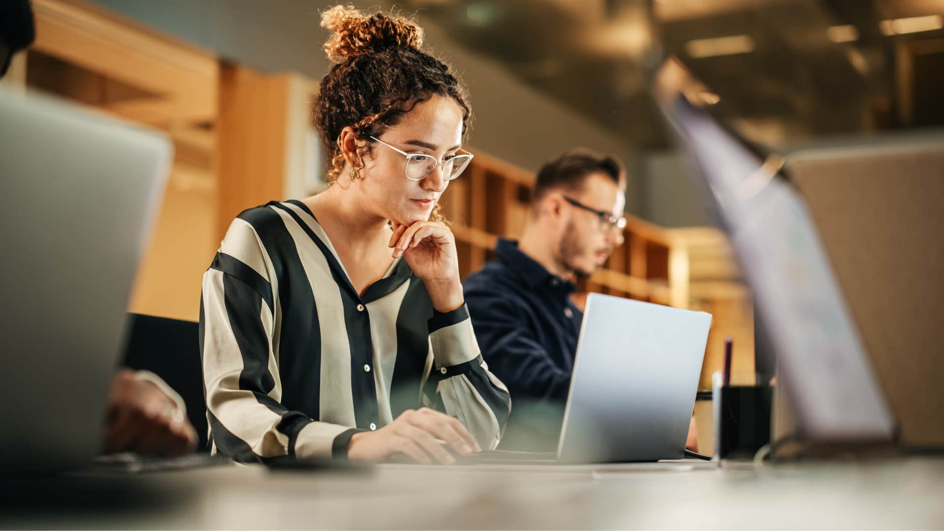 woman on laptop near coworkers as she works 24/7