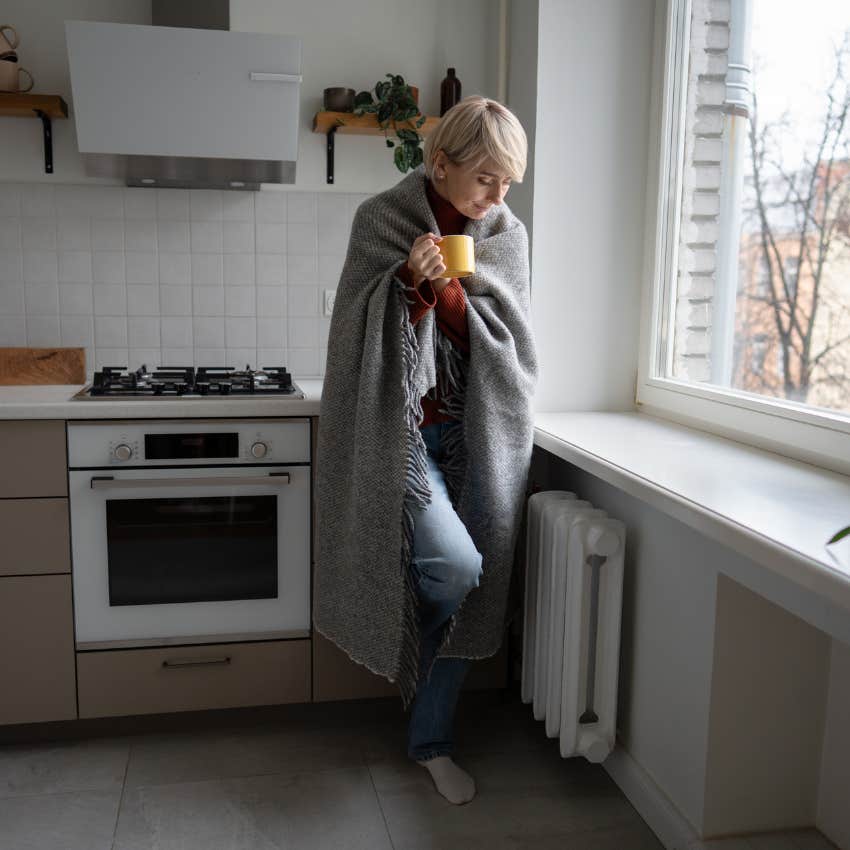 woman cold in her apartment trying to save money wrapped in a blanket
