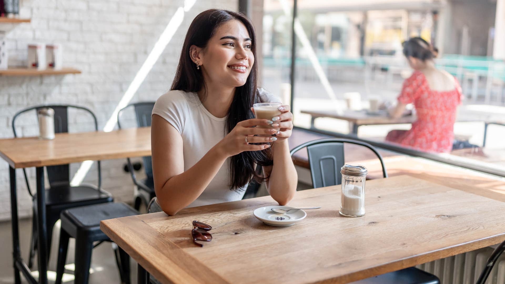 women in white shirt drinking coffee by herself as they're introverted