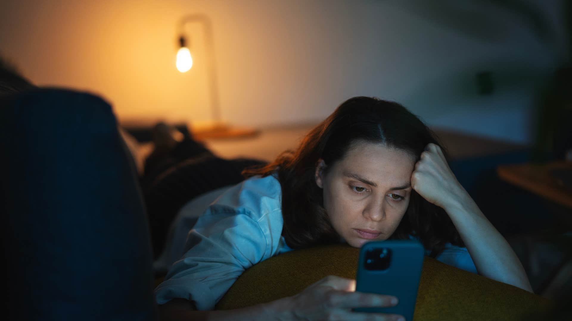 woman who watches videos on her phone before bed because she is attached to her phone