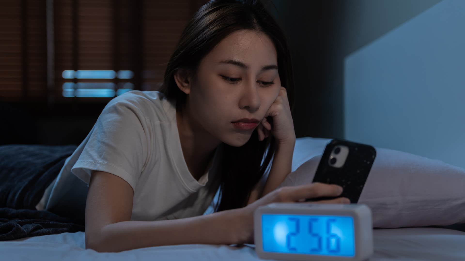 woman who watches videos on her phone before bed because she is a night owl