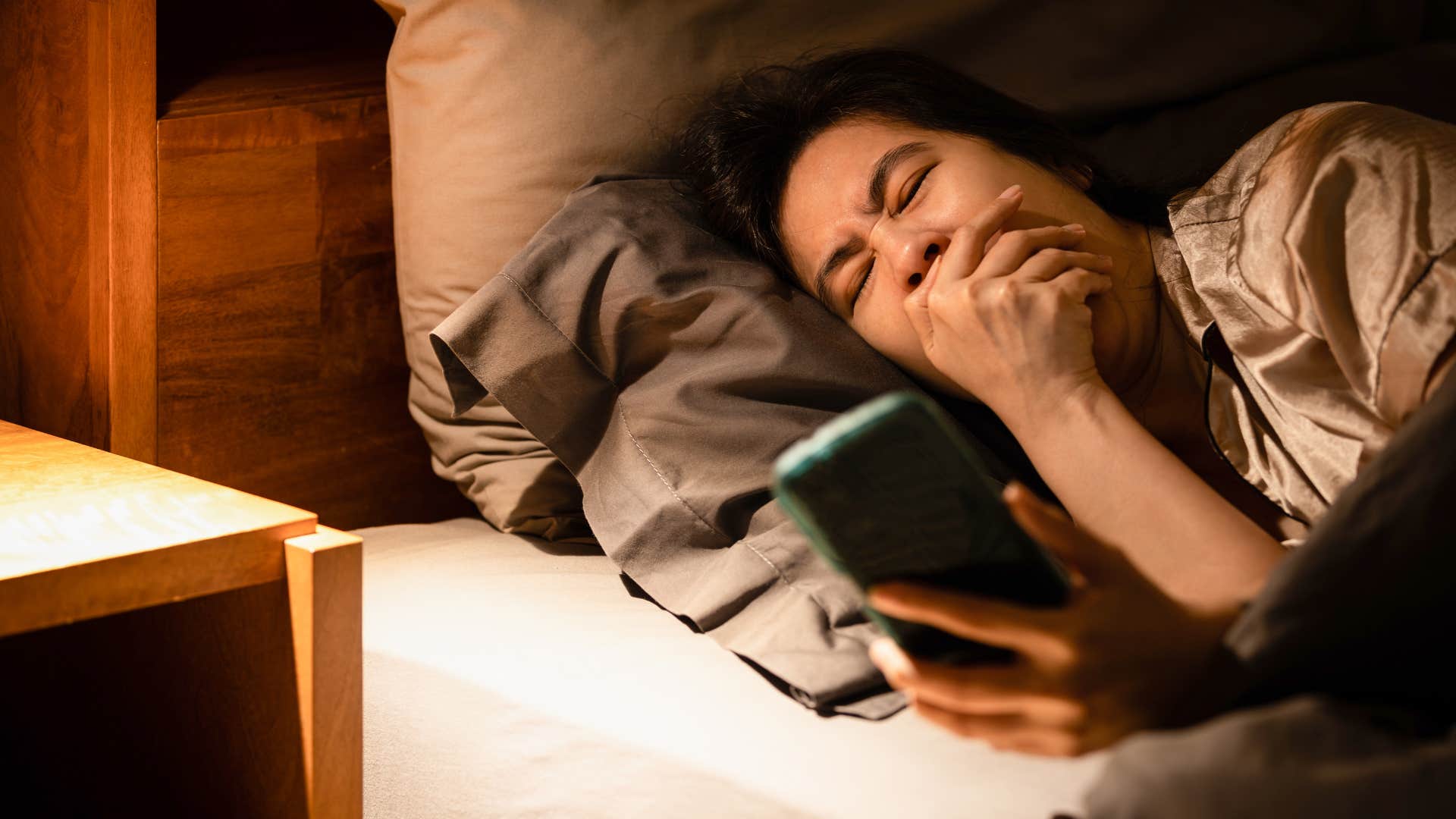 woman who watches videos on her phone before bed because she is procrastinating sleep