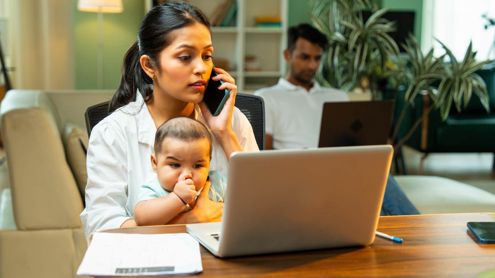mother working and holding her baby at home