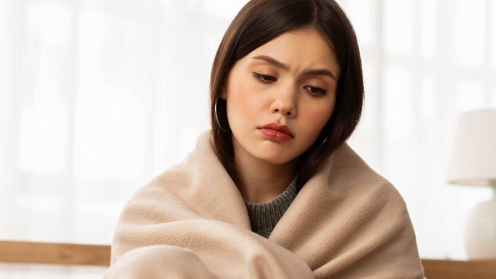 Woman who only thinks of herself looking sad wrapped in a blanket