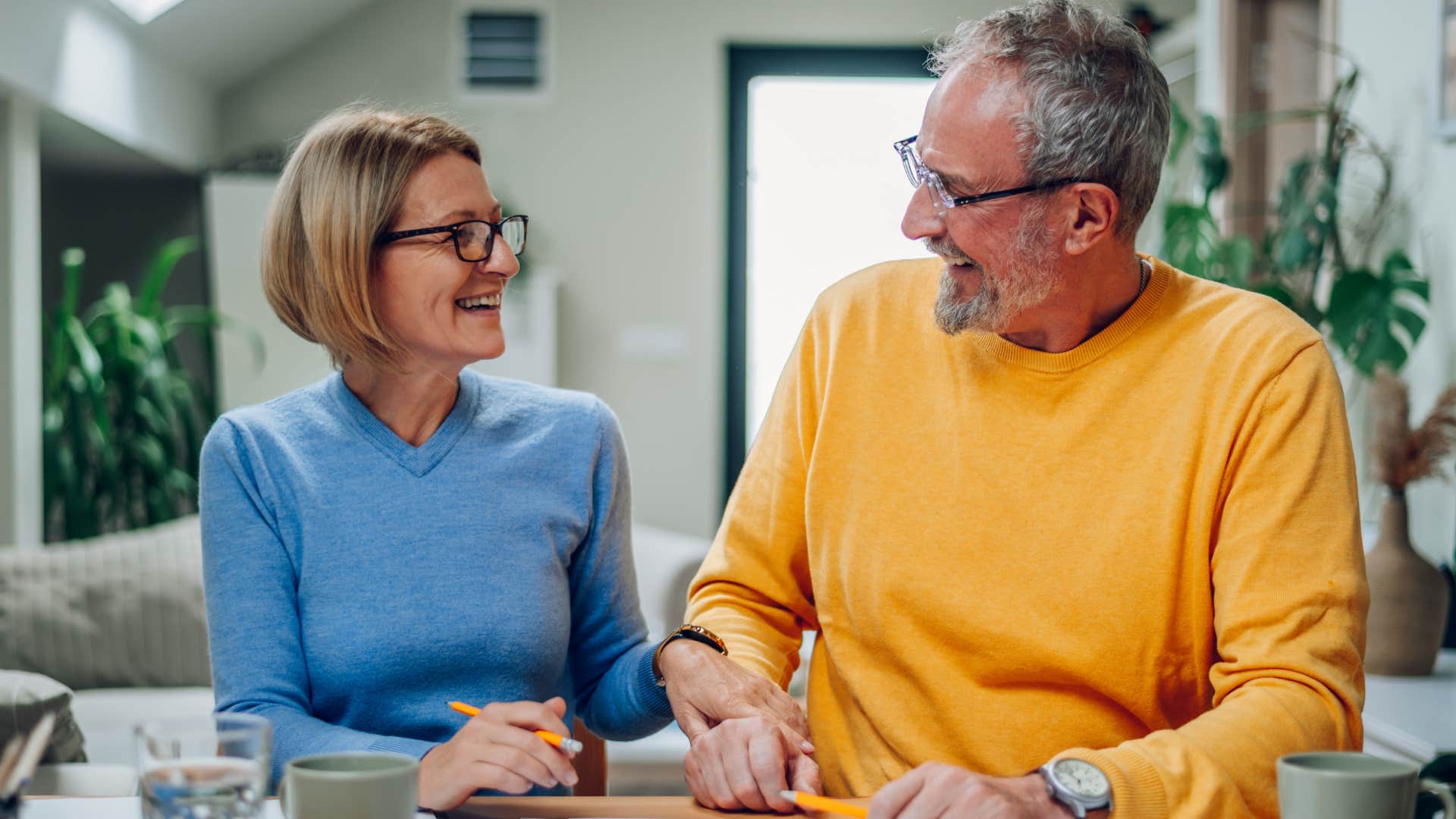 Couple who needs regular quality time smiling at home.