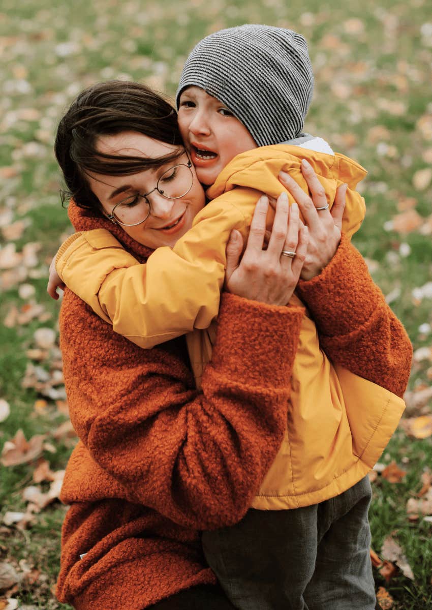 young boy crying in his mom's arms
