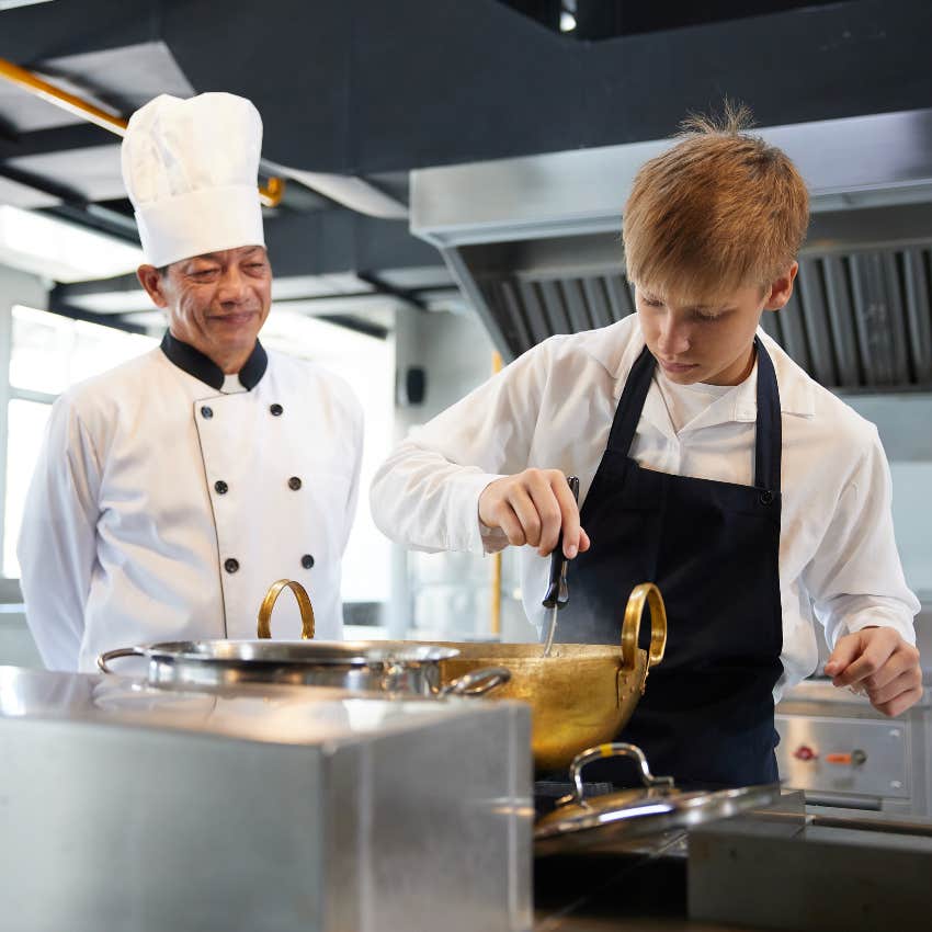 teen boy learning cooking from older chef