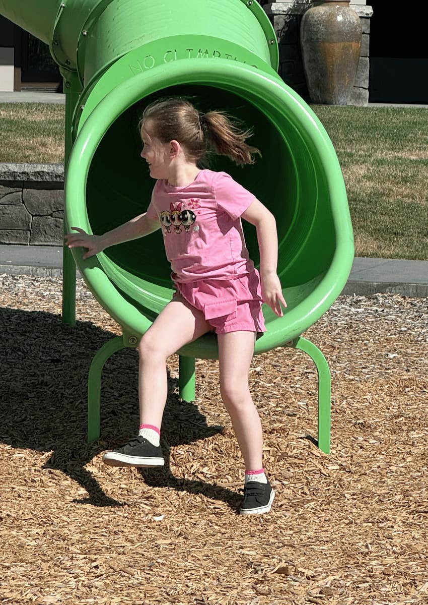 young girl coming out of park kid slide