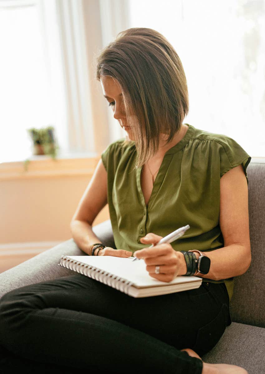 adult woman writing inside of notebook