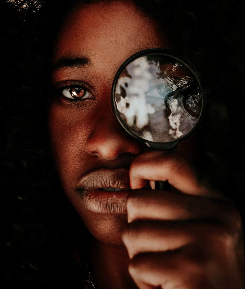 contemplative person hold magnifier to eye showing concept of emotional exploration