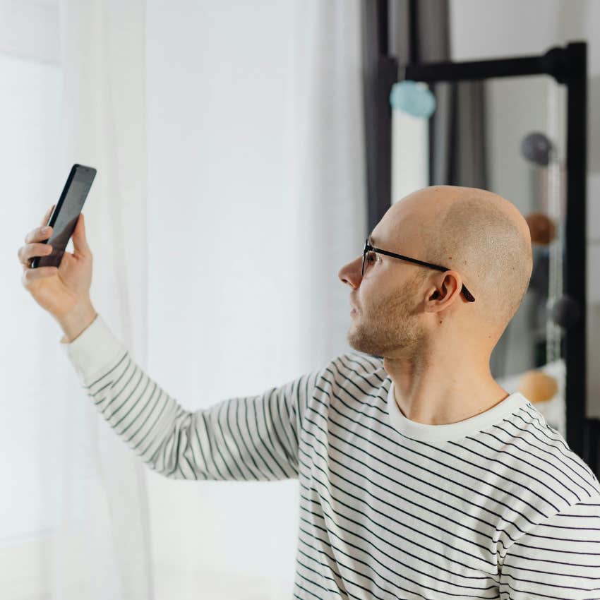 man taking picture to share on bald reddit