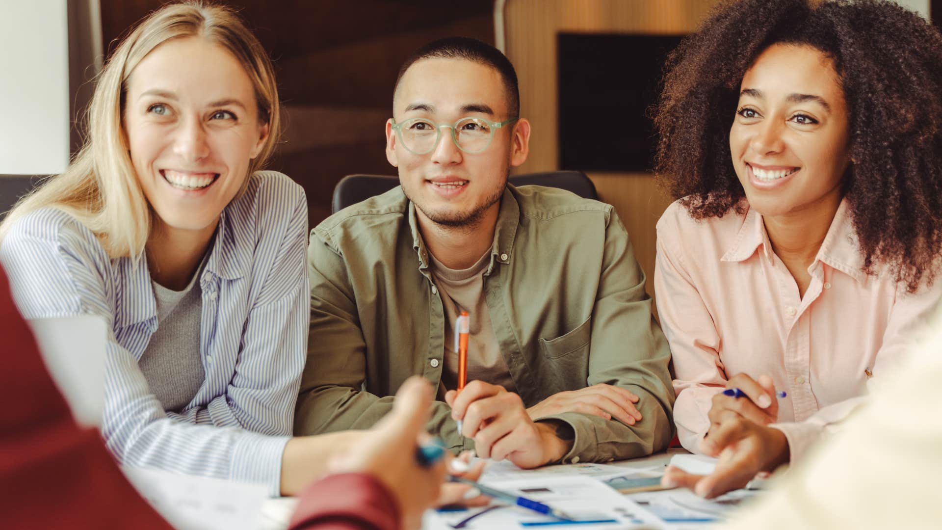 group of colleagues sitting together at work smiling