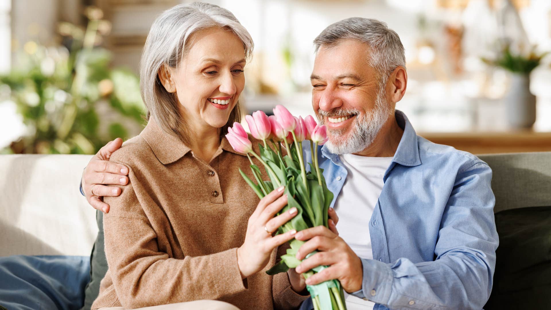 happily married husband giving his wife bouquet of flowers
