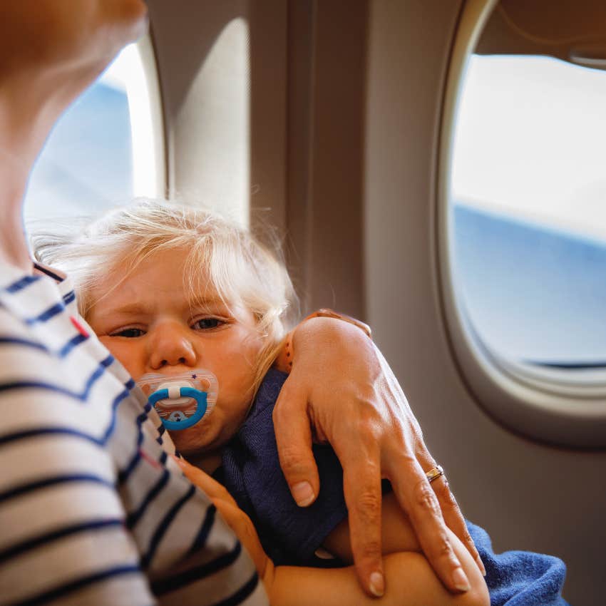 mom trying to comfort her crying toddler after boarding plane first