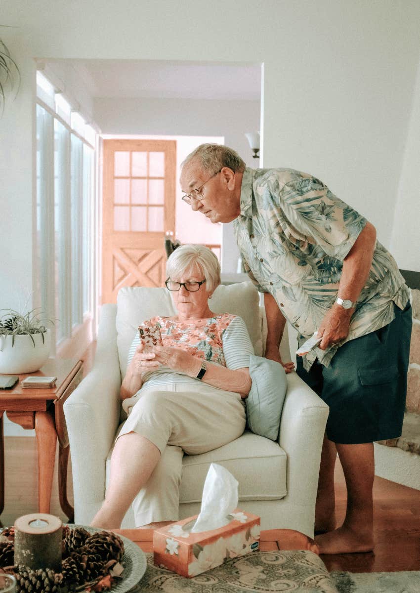 boomer couple looking down at his phone together