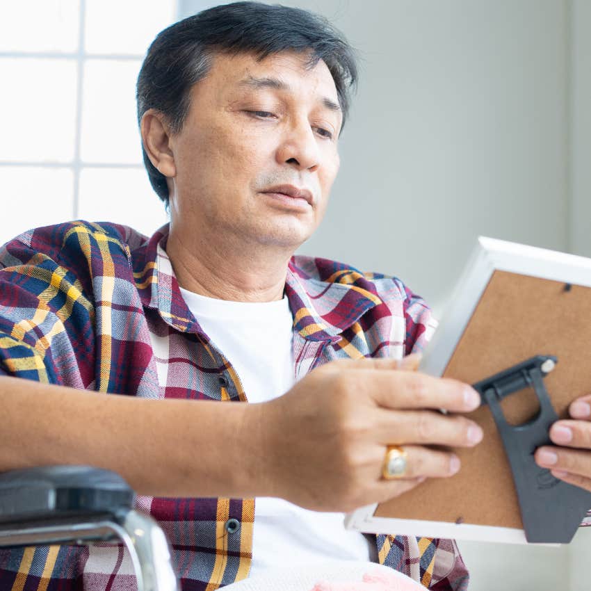 boomer man prone to sitting with nostalgia looking at a framed photo