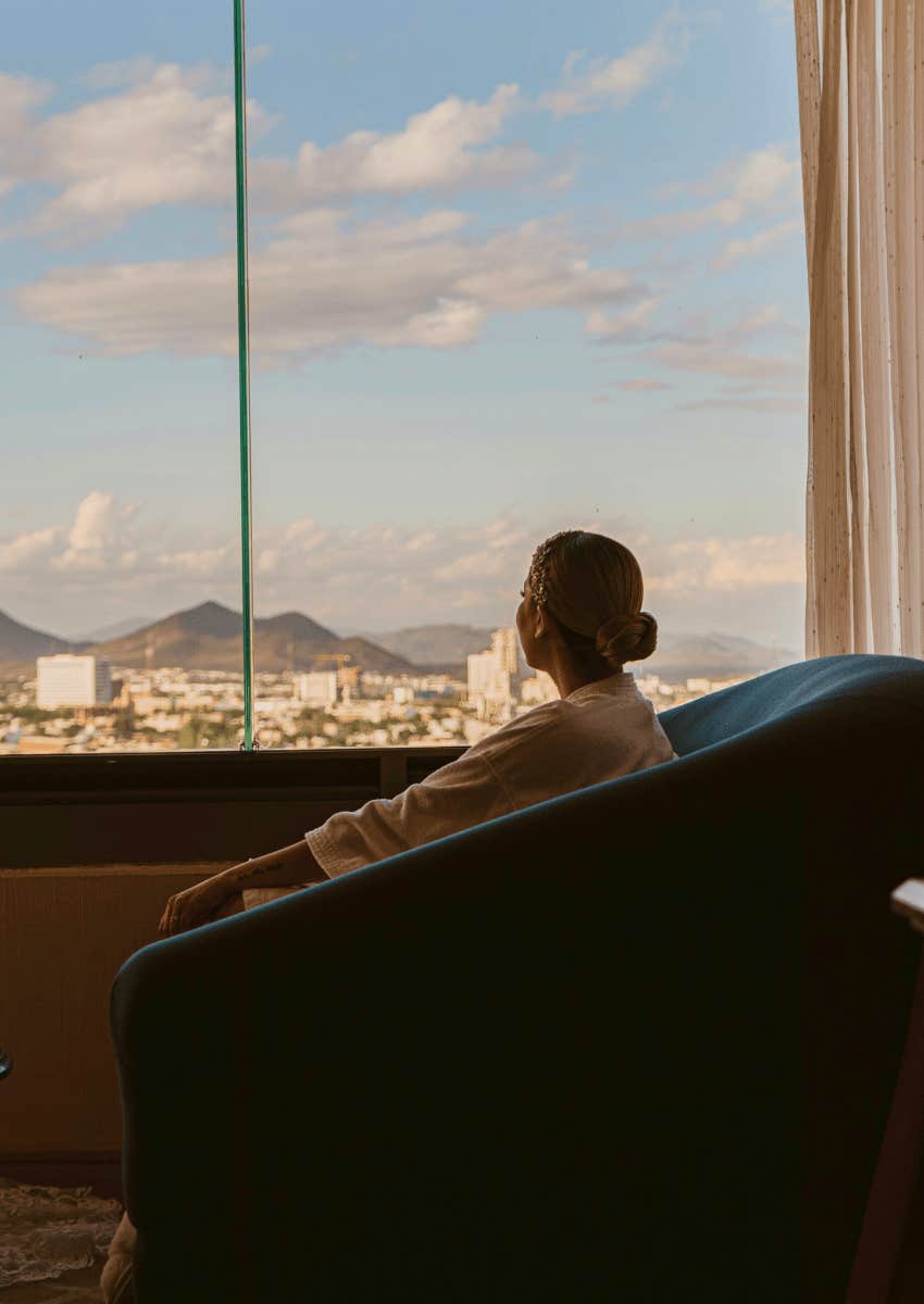 calm woman looking out of window realizing that it's never as bad as it seems