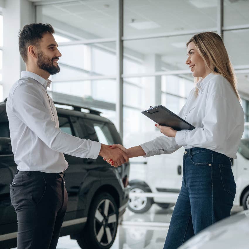 man shaking hands with car saleswoman at dealership