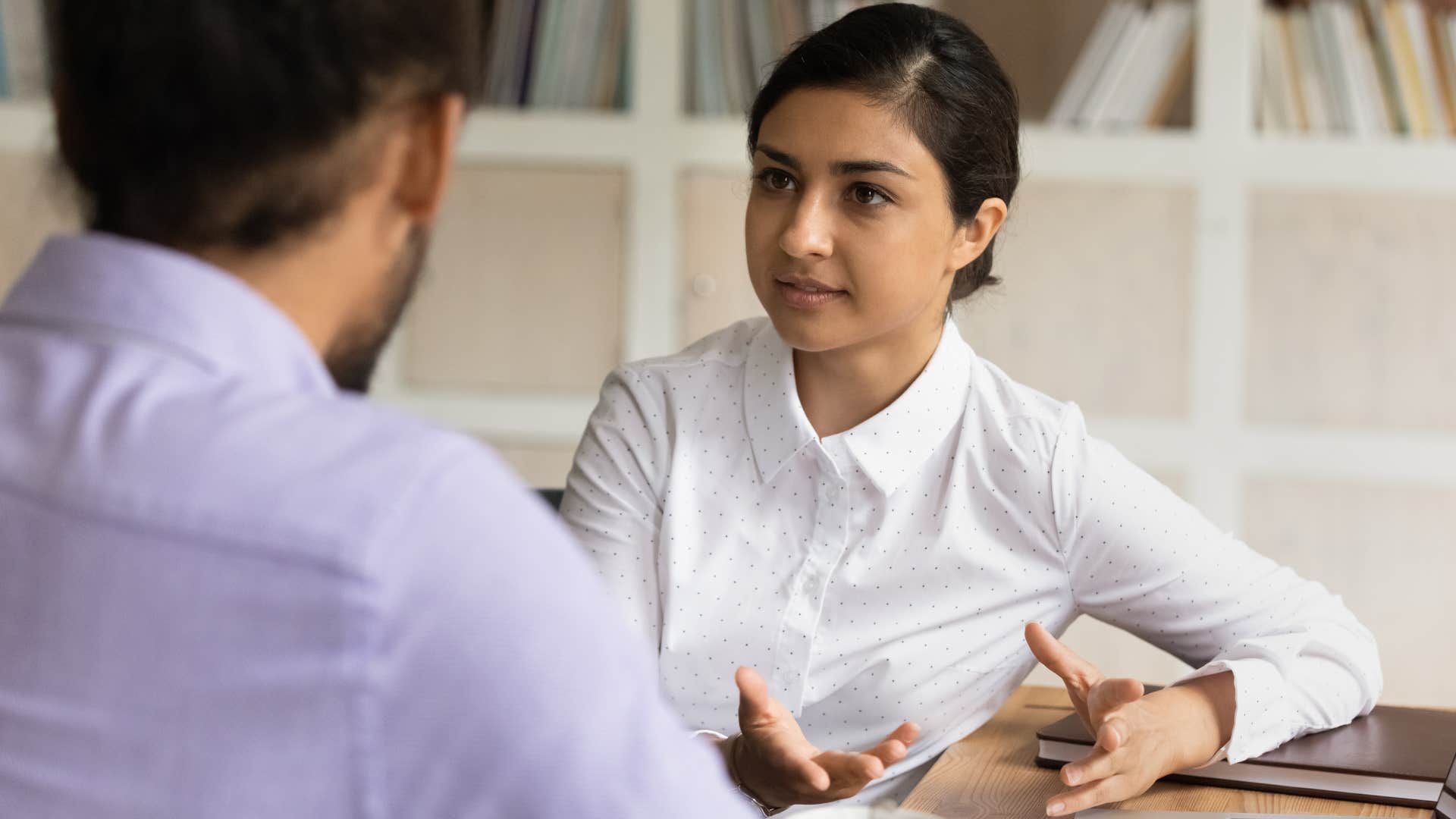 Woman asking "How much money do you make?" to a co-worker.