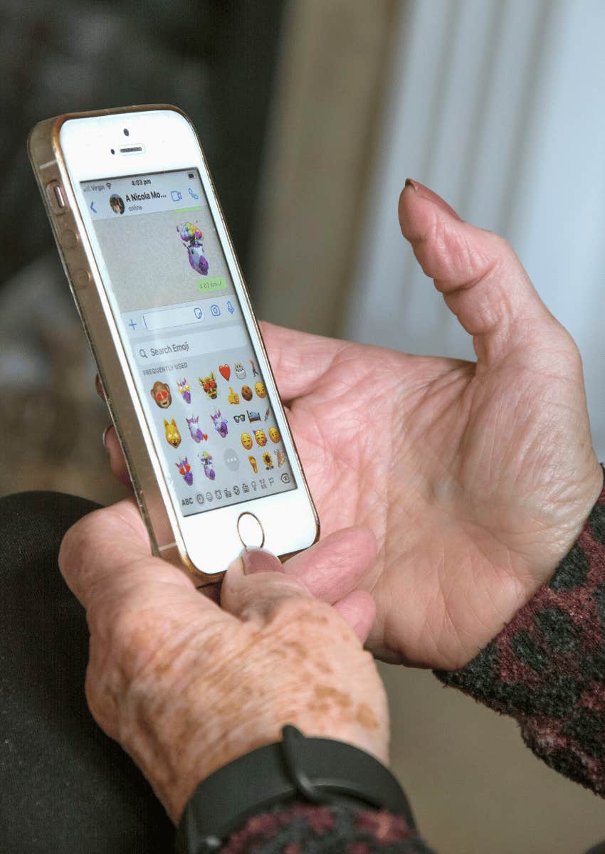 close up of older person's hands texting on phone