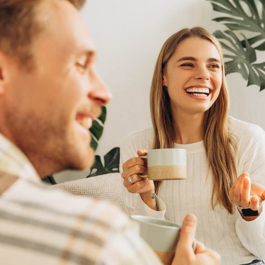 woman laughing holding mug during conversation with man