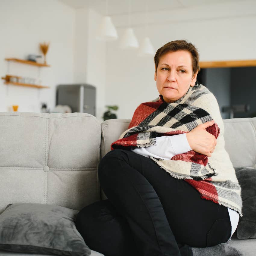 sad woman covered with blanket sitting on couch