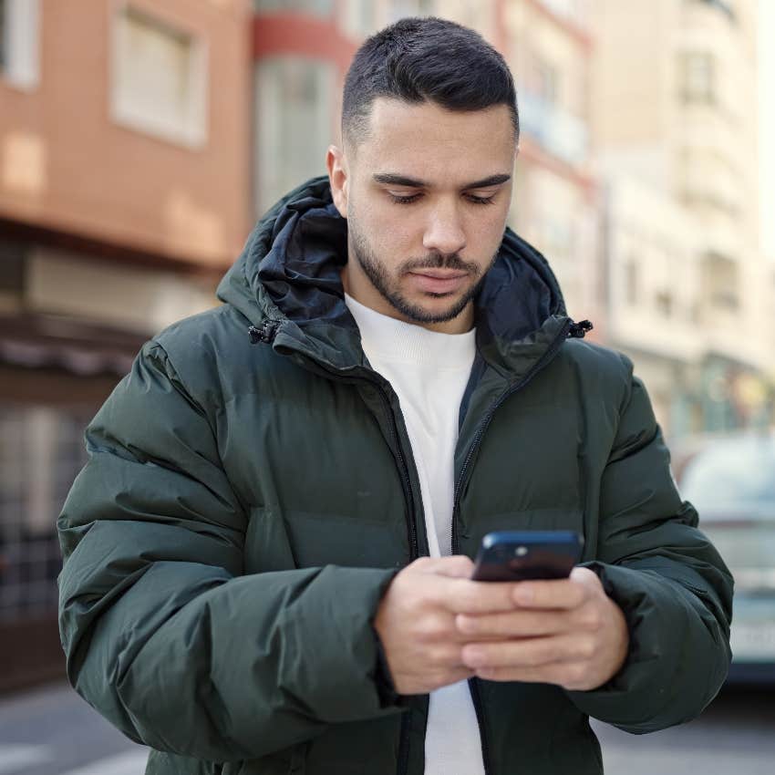 man texting on smartphone walking outside