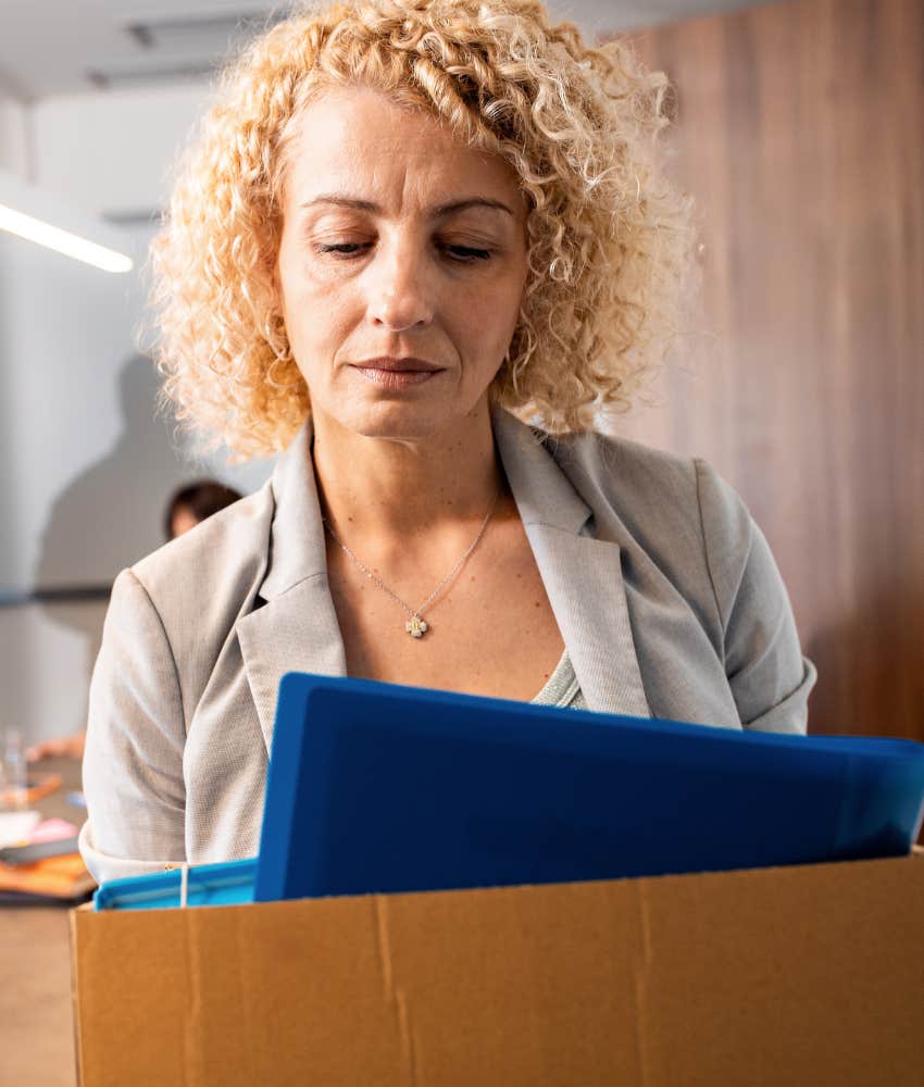 upset person holds box of office supplies showing burden of getting fired