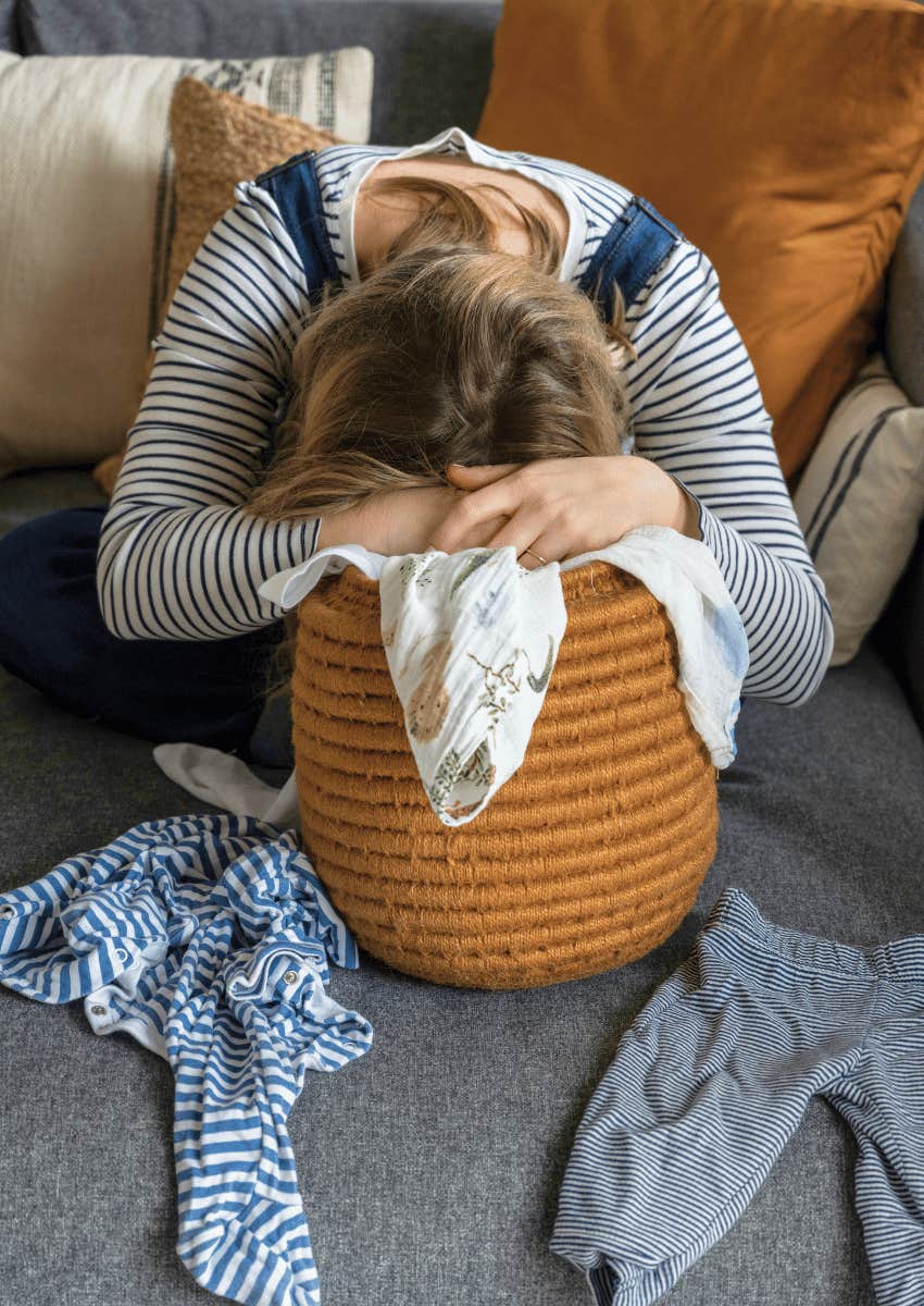 exhausted mom with her head in laundry basket