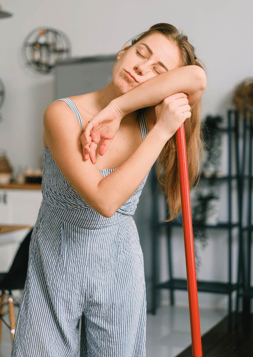 exhausted woman leaning on broom