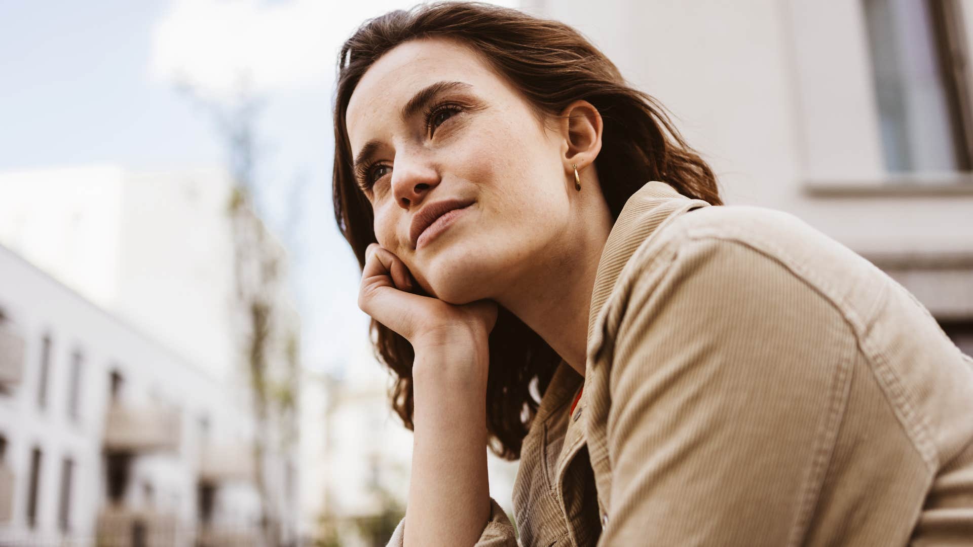 woman who's open to risk-taking smiling at the sky