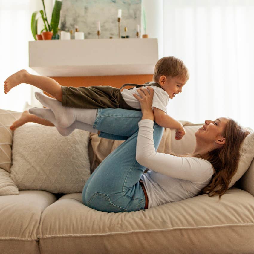 mom playing with son on couch has a full-time nanny for support