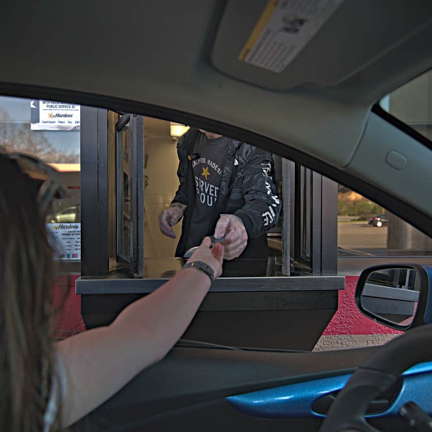 woman paying at fast food drive thru after digging through her wallet wasting time