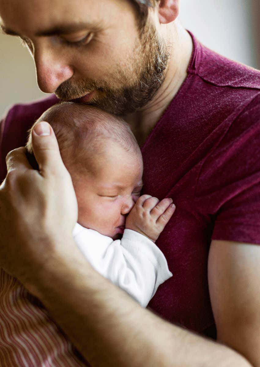 father holding his newborn baby close
