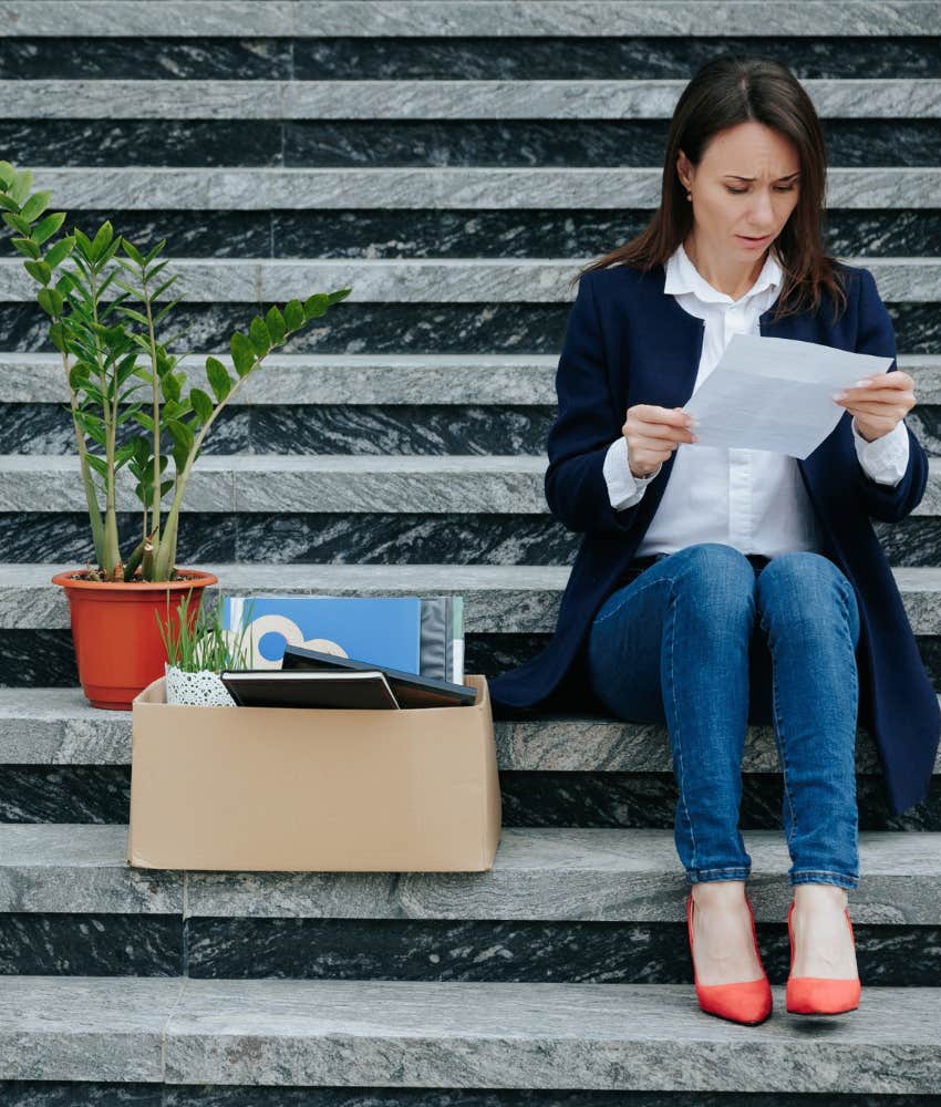 exhausted person sits on steps with box of office supplies showing forced to change