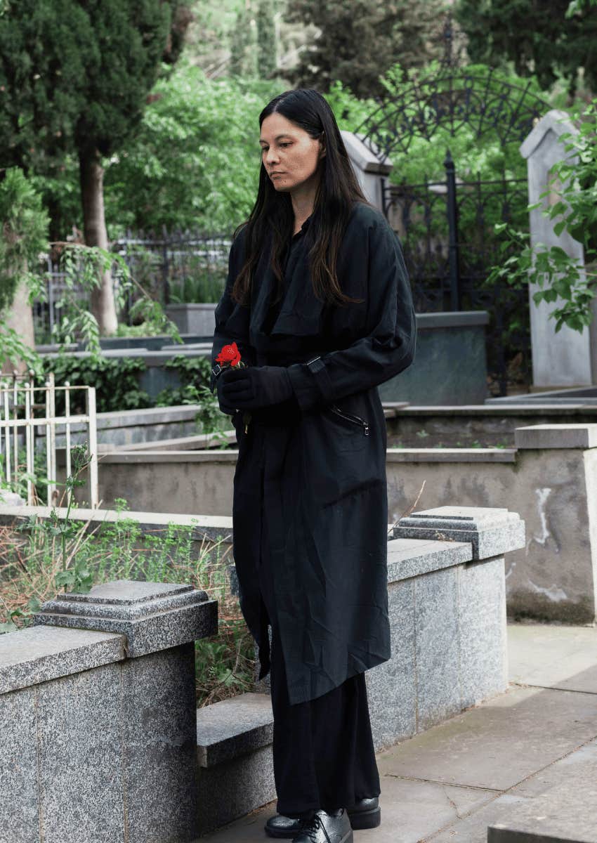 grieving woman leaving a rose at memorial