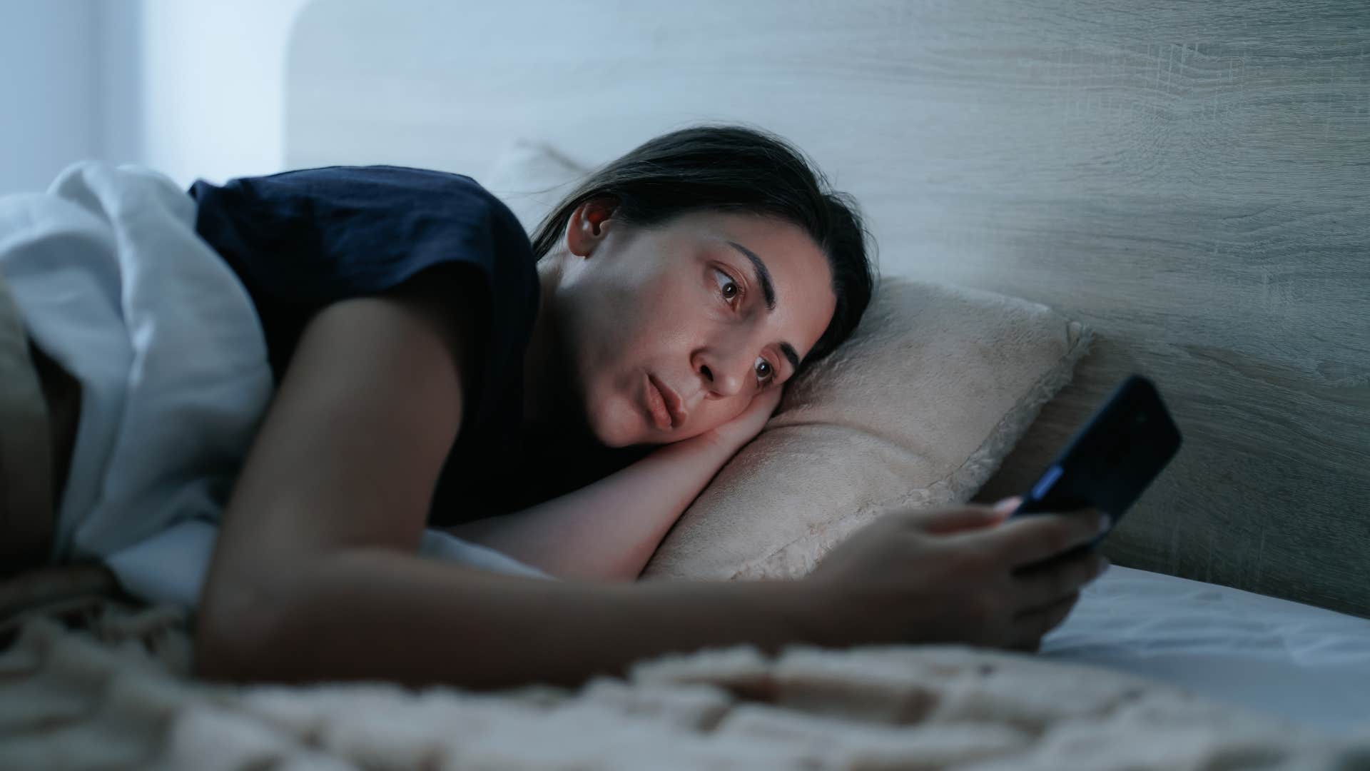newly awake woman letting her phone be her only morning ritual 