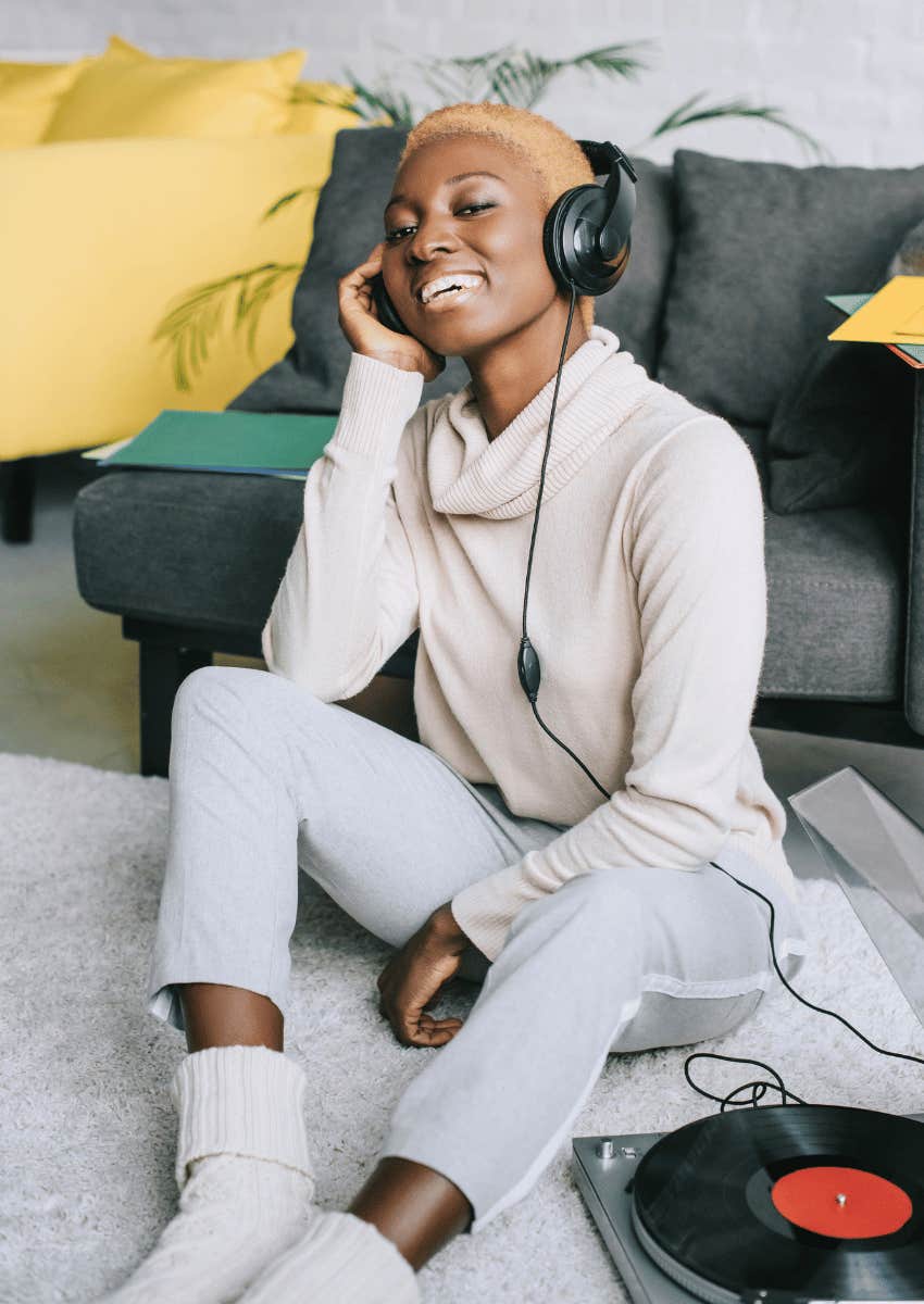 happy woman wearing headphones connected to a record player