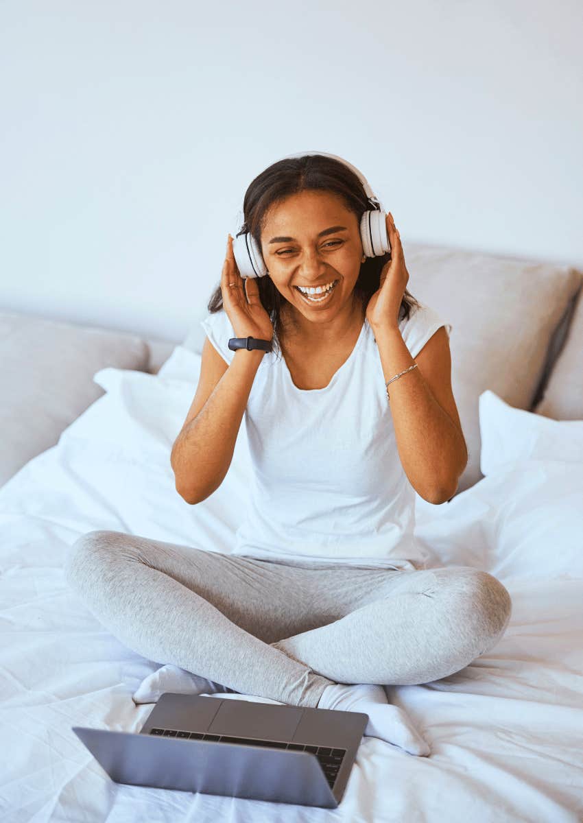 happy young woman sitting with her laptop wearing headphones
