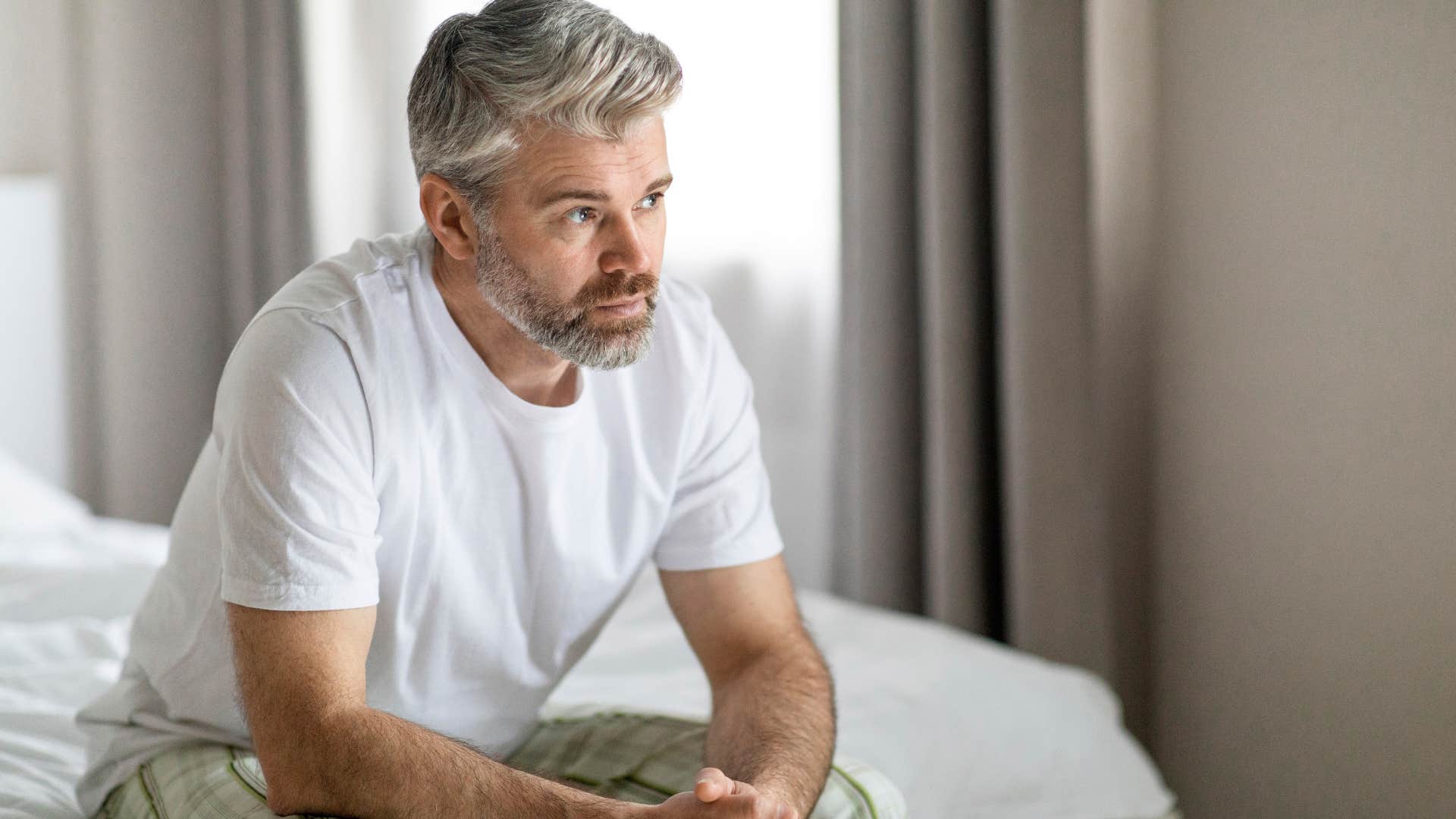 serious man sitting in bed thinking deeply