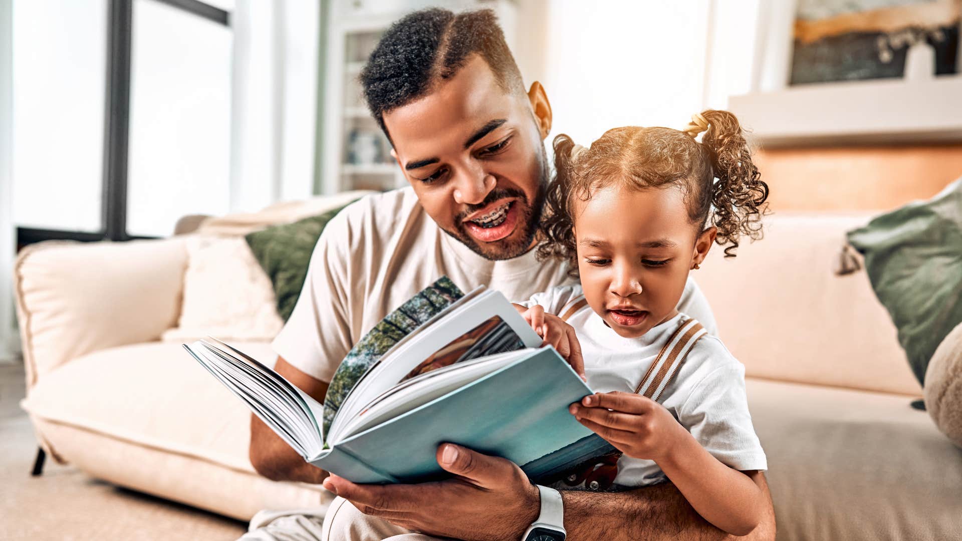 dad reading to daughter to raise her intelligent saying lets read a book