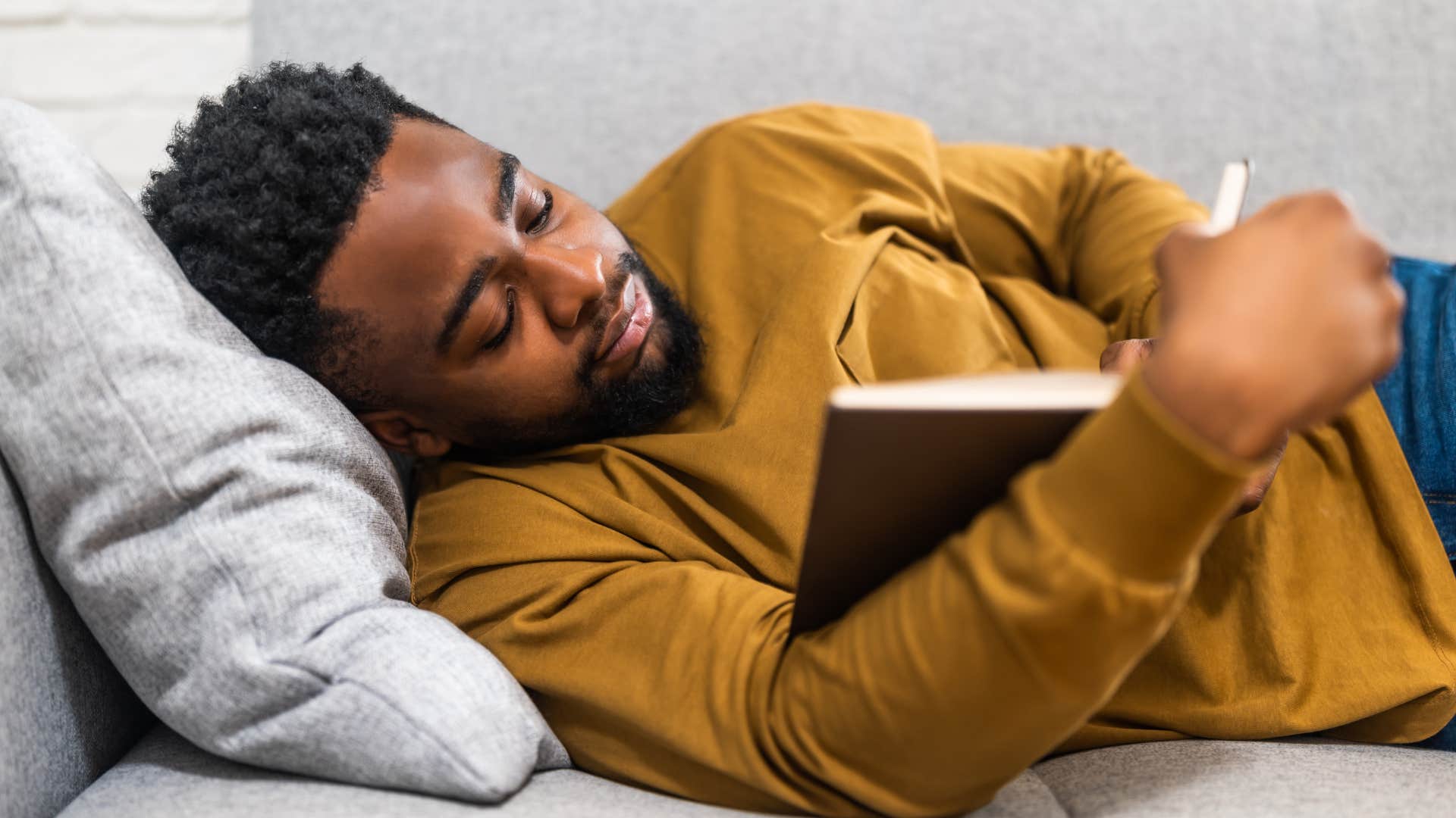 exhausted man saying I need a break while reading on the couch