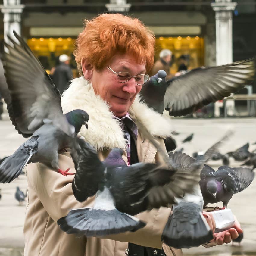 Woman who knows how to handle discomfort feeding pigeons outside