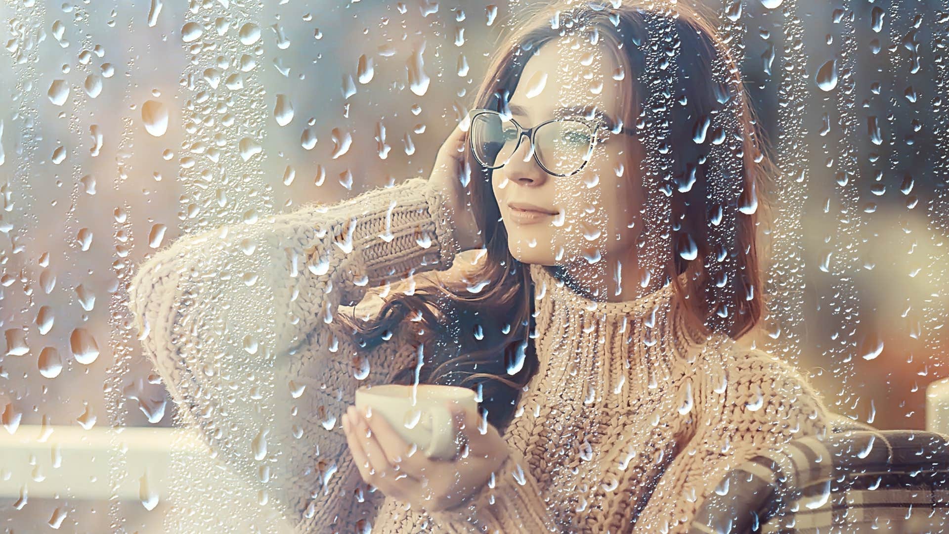 happy introverted woman watching rainy weather from inside