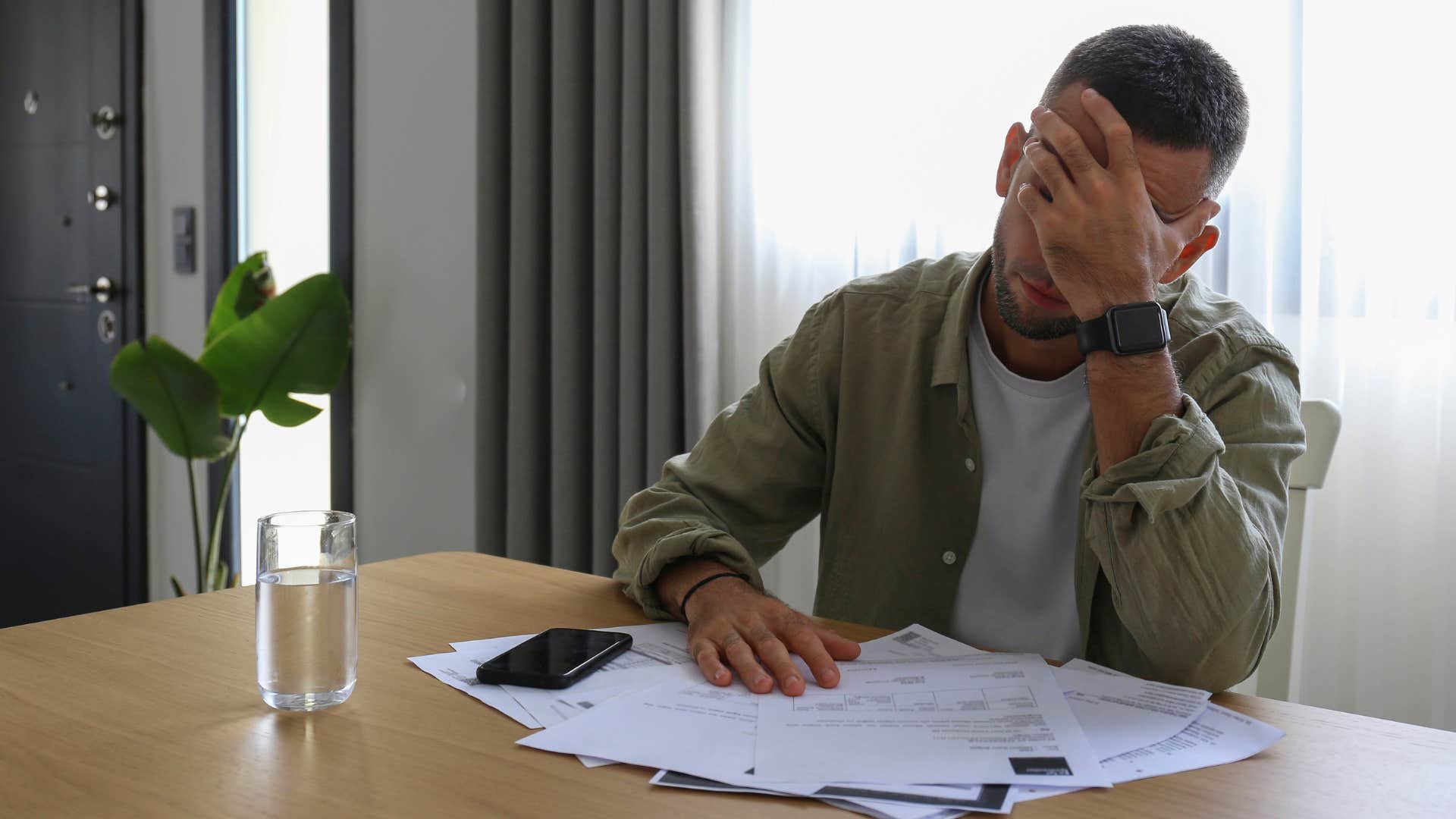 Man struggling with a fear of failure while doing bills.