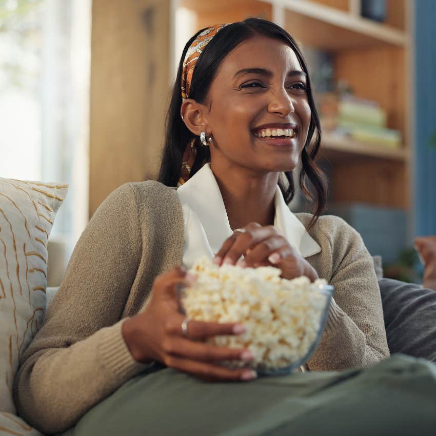 woman eating popcorn and smiling while watching documentary